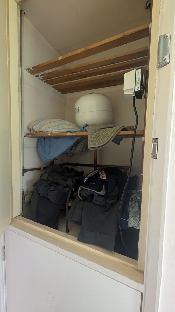 An airing cupboard with a boiler, shelves and stored bags