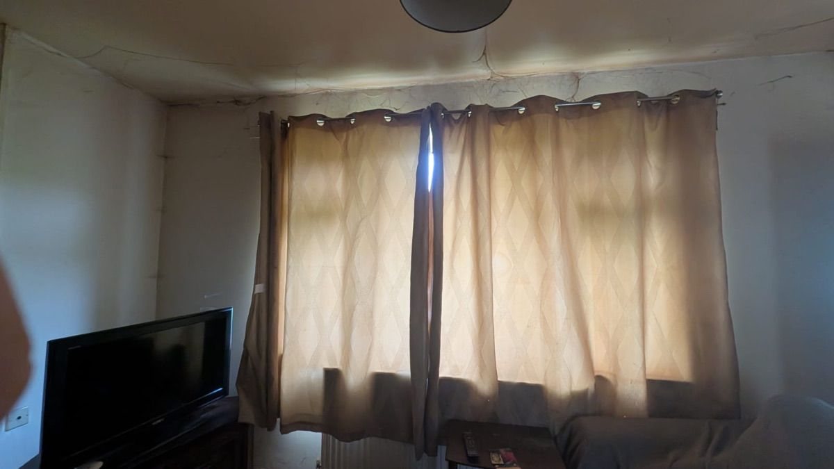 A living room with curtains and a television before any clearance work