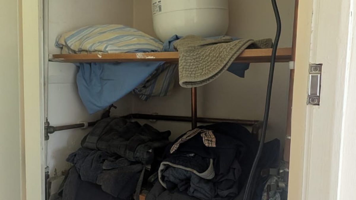 A storage cupboard with shelves, bags and a boiler visible